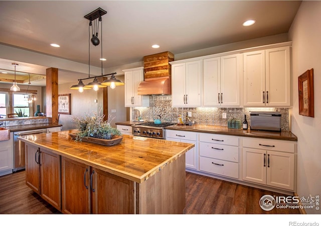 kitchen featuring pendant lighting, a center island, white cabinets, and butcher block counters