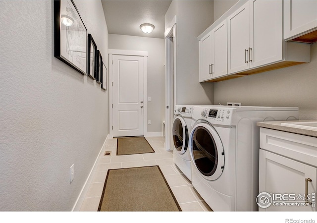 laundry area featuring separate washer and dryer, light tile patterned floors, and cabinets