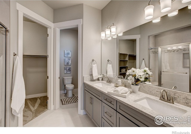 bathroom featuring vanity, toilet, tile patterned flooring, and a shower with door