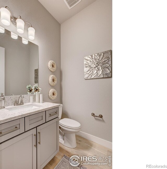 bathroom featuring vanity, hardwood / wood-style floors, and toilet