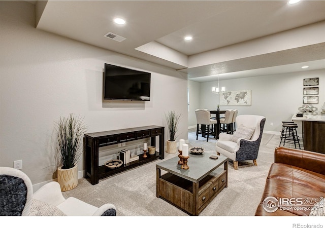 carpeted living room with an inviting chandelier