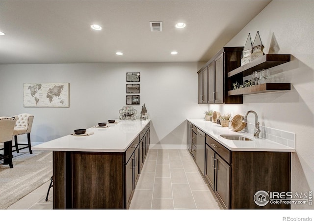 kitchen with dark brown cabinetry, sink, a kitchen breakfast bar, and kitchen peninsula