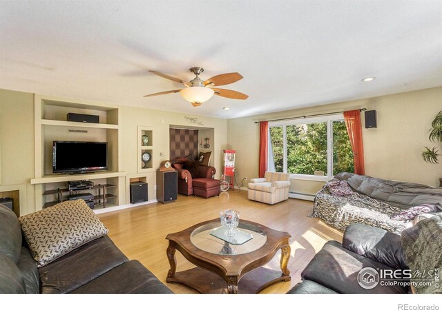 living room featuring light wood-type flooring, a baseboard radiator, ceiling fan, and built in features