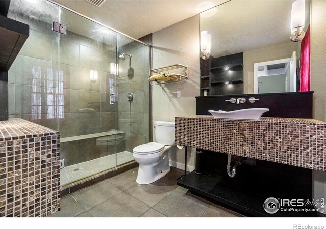 bathroom with tile patterned flooring, toilet, a shower with shower door, and vanity