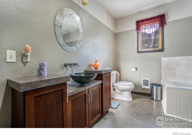 bathroom with tile patterned flooring, a bathing tub, vanity, and toilet