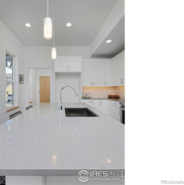 kitchen featuring tasteful backsplash, hanging light fixtures, sink, electric range, and white cabinetry