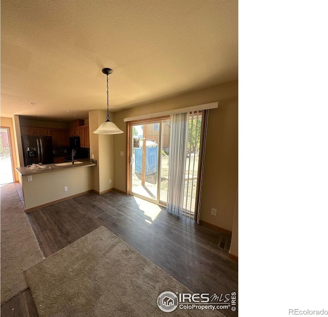 unfurnished living room featuring hardwood / wood-style flooring, sink, and a textured ceiling