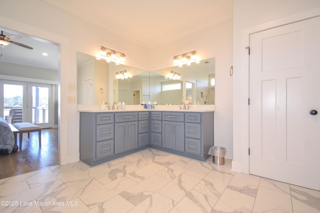 bathroom with marble finish floor, a ceiling fan, a sink, connected bathroom, and double vanity