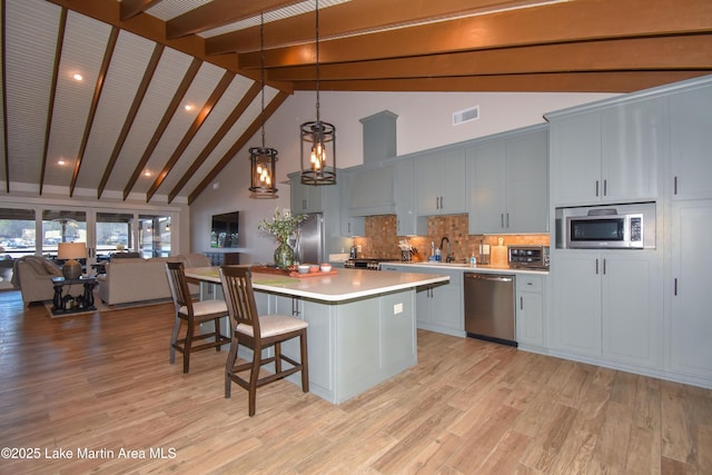 kitchen with premium range hood, visible vents, open floor plan, stainless steel appliances, and light countertops