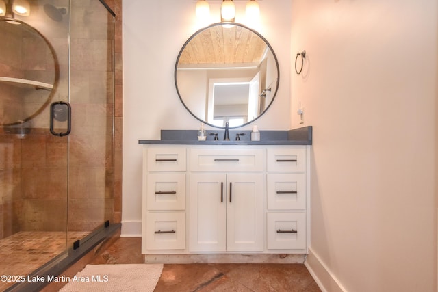 bathroom with vanity, a shower stall, and baseboards