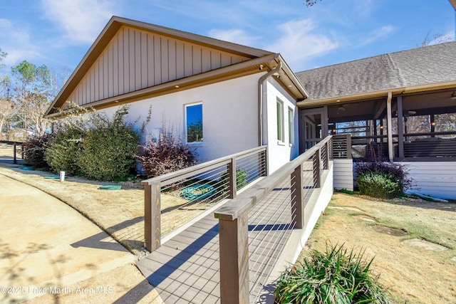 view of side of home with roof with shingles and a sunroom