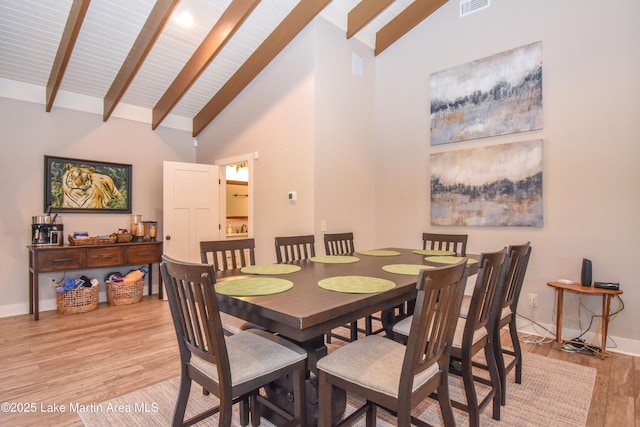 dining area with beam ceiling, baseboards, high vaulted ceiling, and light wood-style floors