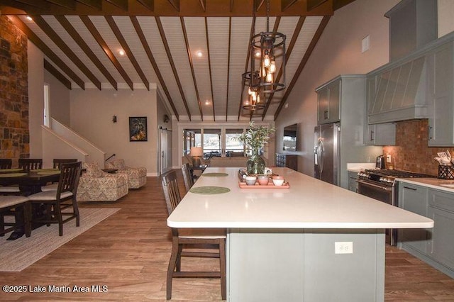 kitchen with light wood-type flooring, light countertops, gray cabinets, appliances with stainless steel finishes, and high vaulted ceiling