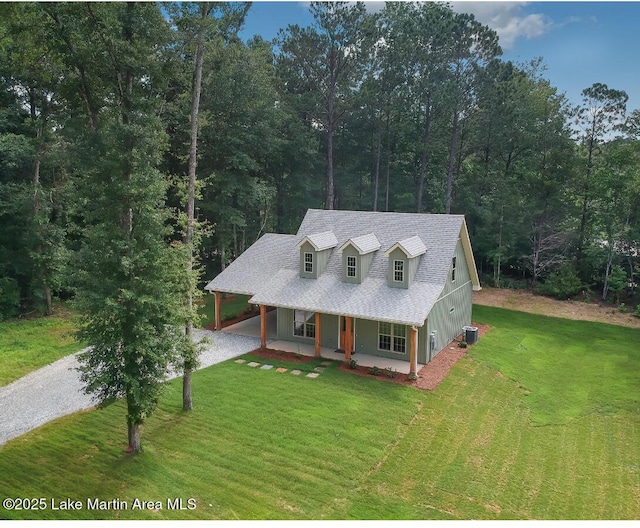 27 Bob Lo Dr, Dadeville, AL 36853 - view of front facade featuring gravel driveway, covered porch, a front yard, a shingled roof, and a forest view