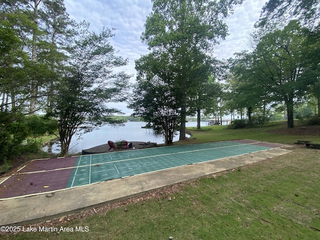 view of sport court with a yard and a water view