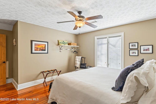 bedroom featuring hardwood / wood-style floors, a textured ceiling, and ceiling fan