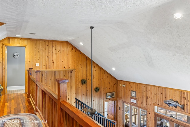 corridor featuring vaulted ceiling and a textured ceiling