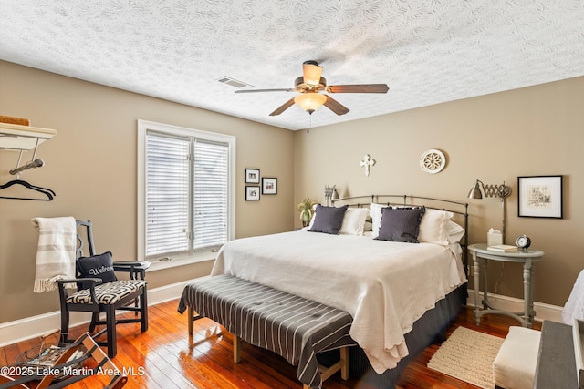 bedroom with ceiling fan, hardwood / wood-style floors, and a textured ceiling