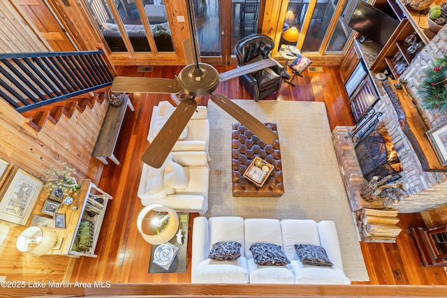 living room featuring a towering ceiling, ceiling fan, and wooden walls