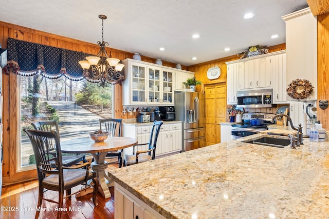 kitchen with white cabinets, dishwasher, wood walls, and kitchen peninsula