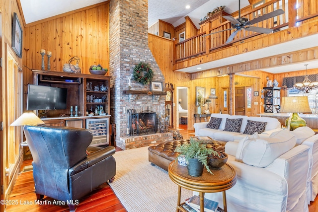 living room featuring a towering ceiling, ceiling fan with notable chandelier, wooden walls, and wood-type flooring