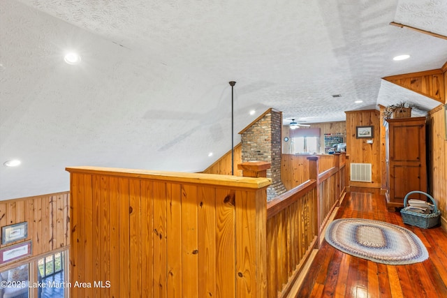 office area with wooden walls, dark wood-type flooring, a textured ceiling, and ceiling fan