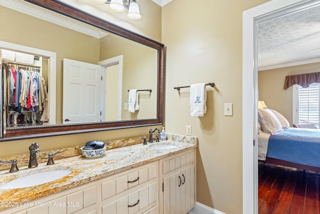 bathroom featuring a textured ceiling, vanity, crown molding, and hardwood / wood-style floors