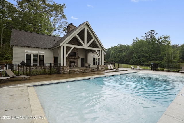 view of swimming pool with a stone fireplace and a patio