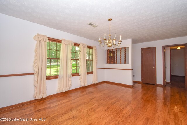 300 Hornsby Dr, Tallassee, AL 36078 - spare room with wood finished floors, a chandelier, a textured ceiling, and baseboards