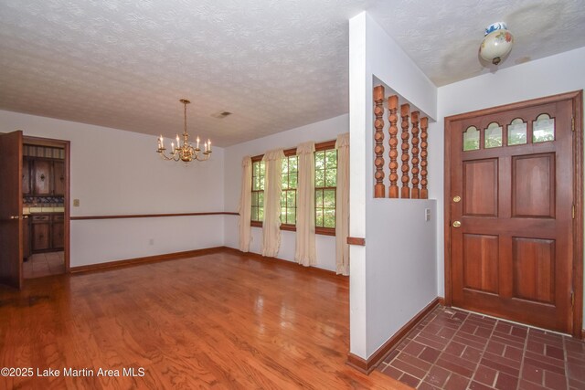 300 Hornsby Dr, Tallassee, AL 36078 - foyer entrance featuring a chandelier, baseboards, a textured ceiling, and dark wood-type flooring