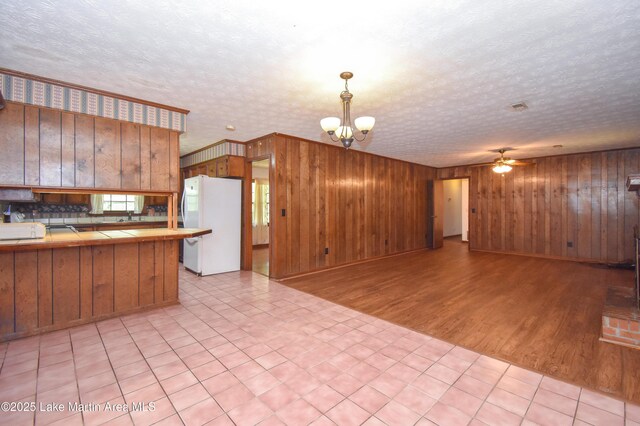 300 Hornsby Dr, Tallassee, AL 36078 - kitchen with freestanding refrigerator, tile countertops, open floor plan, a chandelier, and wooden walls