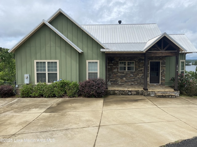 ranch-style house with a porch, board and batten siding, metal roof, and stone siding