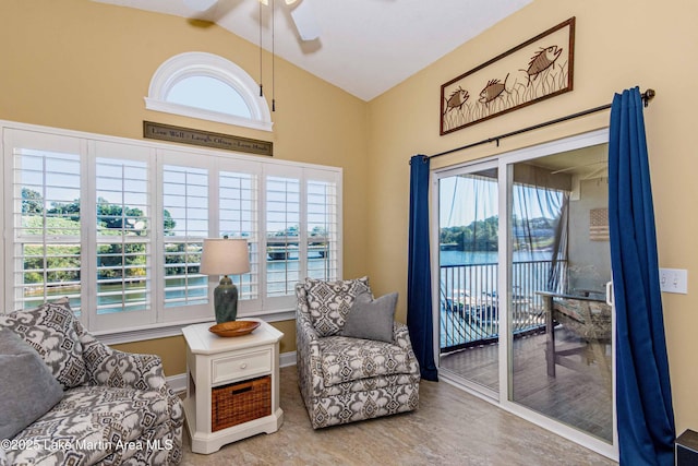 sitting room with a ceiling fan, baseboards, and vaulted ceiling