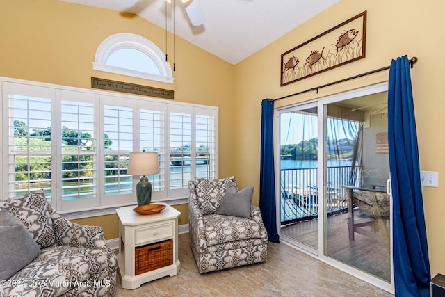 sitting room with ceiling fan, a water view, and high vaulted ceiling