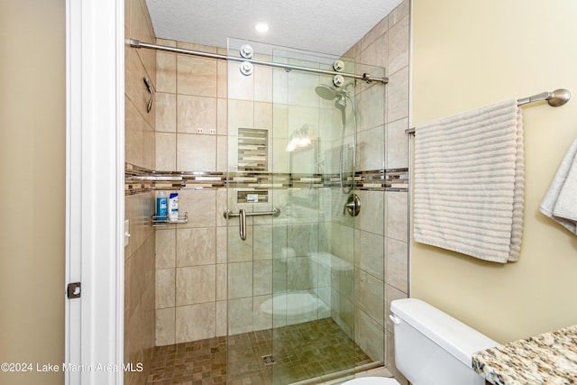 bathroom with toilet, an enclosed shower, and a textured ceiling