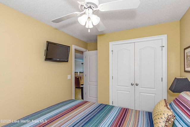 carpeted bedroom featuring ceiling fan, a textured ceiling, and a closet