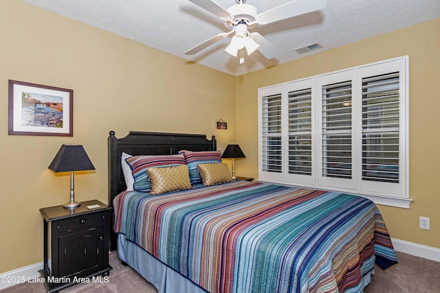 bedroom with a textured ceiling, baseboards, visible vents, carpet, and a ceiling fan