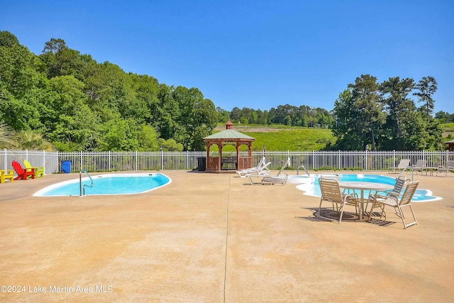 pool with a gazebo, a patio area, and fence