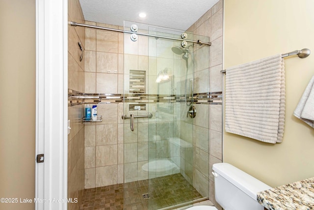 full bathroom with a shower stall, toilet, and a textured ceiling