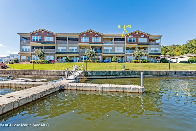 view of dock with a lawn and a water view