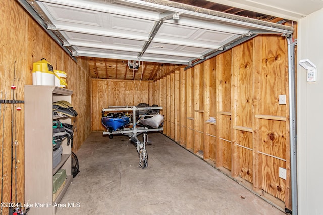 garage with a garage door opener and wooden walls