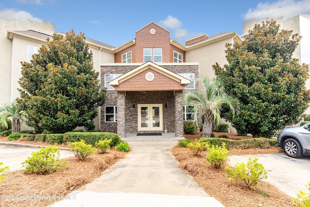 view of front of property with stone siding, french doors, and stucco siding