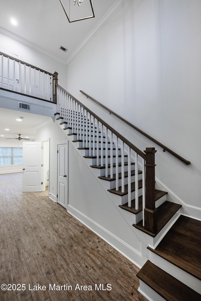 stairway featuring hardwood / wood-style flooring, ornamental molding, and ceiling fan