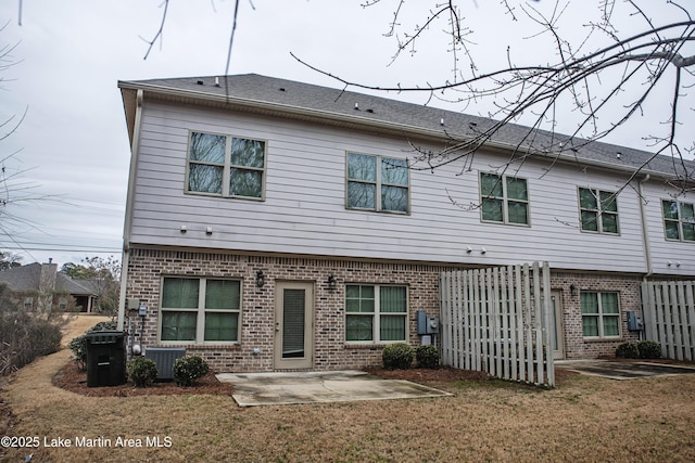 back of house featuring cooling unit, a lawn, and a patio