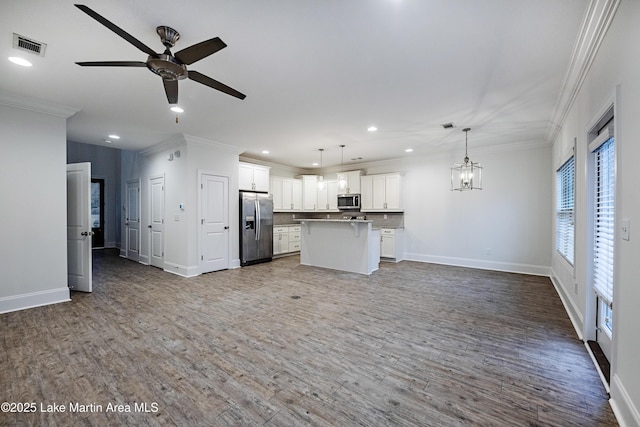 kitchen with crown molding, appliances with stainless steel finishes, white cabinets, a kitchen island, and decorative light fixtures