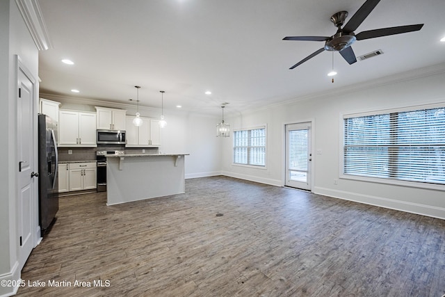 kitchen featuring decorative light fixtures, white cabinetry, a breakfast bar area, a kitchen island with sink, and stainless steel appliances