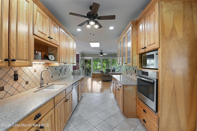 kitchen with light stone counters, sink, light tile patterned flooring, and stainless steel appliances