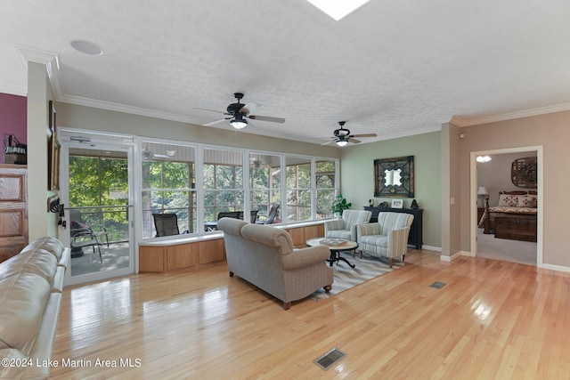 living room featuring a textured ceiling, ceiling fan, light wood-type flooring, and crown molding