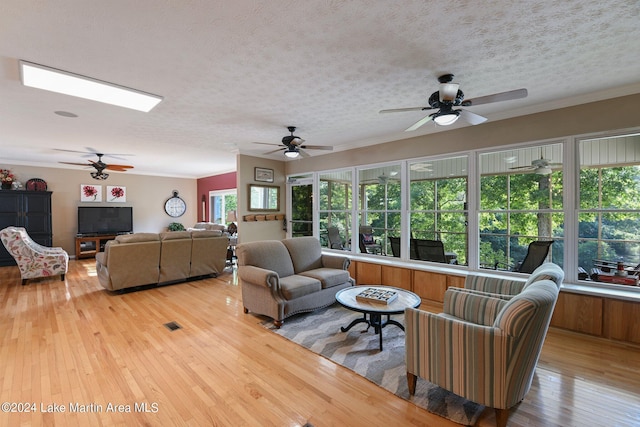 living room featuring a textured ceiling, ceiling fan, light hardwood / wood-style floors, and crown molding