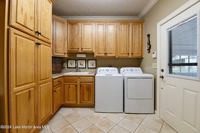 laundry area featuring cabinets, a textured ceiling, crown molding, sink, and washer and dryer